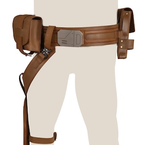 Könnte beinhalten: Ein brauner Ledergürtel mit einer silbernen Schnalle und zwei braunen Ledertaschen. Der Gürtel hat einen Oberschenkelriemen mit einer Tasche.