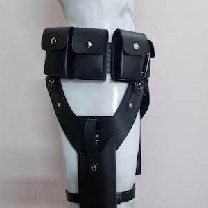 May include: A black utility belt featuring three rectangular pouches with silver snap closures attached to the waist, connected to a vertical holster on the thigh with a matching silver snap, all constructed from a smooth, matte black material.