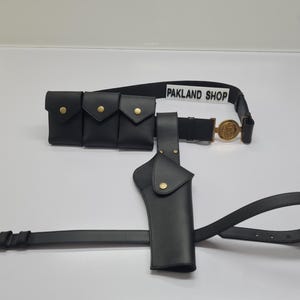 Peut inclure: Ceinture utilitaire en cuir noir avec trois pochettes, un étui et une ceinture avec une boucle dorée. La ceinture porte le texte "PAKLAND SHOP".