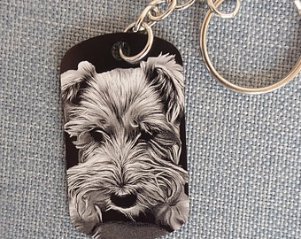 May include: A black metal keychain with a silver chain and a black and white photo of a dog's face.