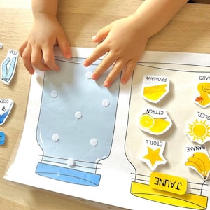May include: A learning activity for children featuring two jars, one labelled "Blue" and the other "Yellow".  The jars are empty and there are various blue and yellow images to be sorted into the correct jar.  The blue images include a butterfly, a whale, a bird, a water drop, a pair of jeans, and a pool.  The yellow images include a banana, a star, a lemon, a sun, a duck, and a piece of cheese.
