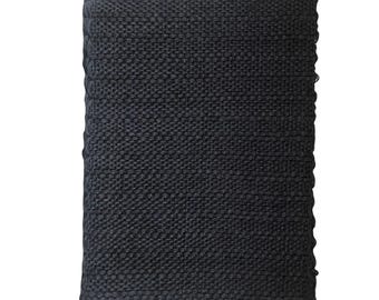 Puede incluir: Un textil rectangular negro tejido con una superficie texturizada. La tela parece estar tejida de forma apretada, creando una apariencia oscura y sólida. Los bordes están cuidadosamente acabados, lo que sugiere un producto terminado.