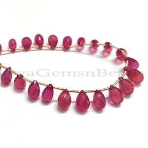 以下が含まれることがあります： 涙の形をしたピンクの宝石ビーズが20個、糸に通されています。ビーズは金色のワイヤーに通されています。