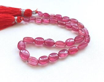 May include: A strand of pink oval-shaped gemstone beads with red tassels at the ends.