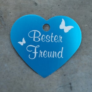May include: A blue heart-shaped metal tag with the text "Best Friend" and two white butterfly silhouettes.