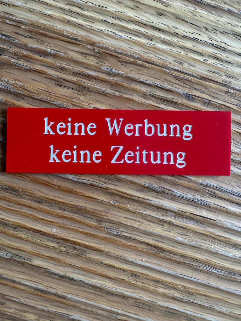 K&ouml;nnte beinhalten: Ein rotes rechteckiges Schild mit wei&szlig;em Text, auf dem "keine Werbung keine Zeitung" steht.