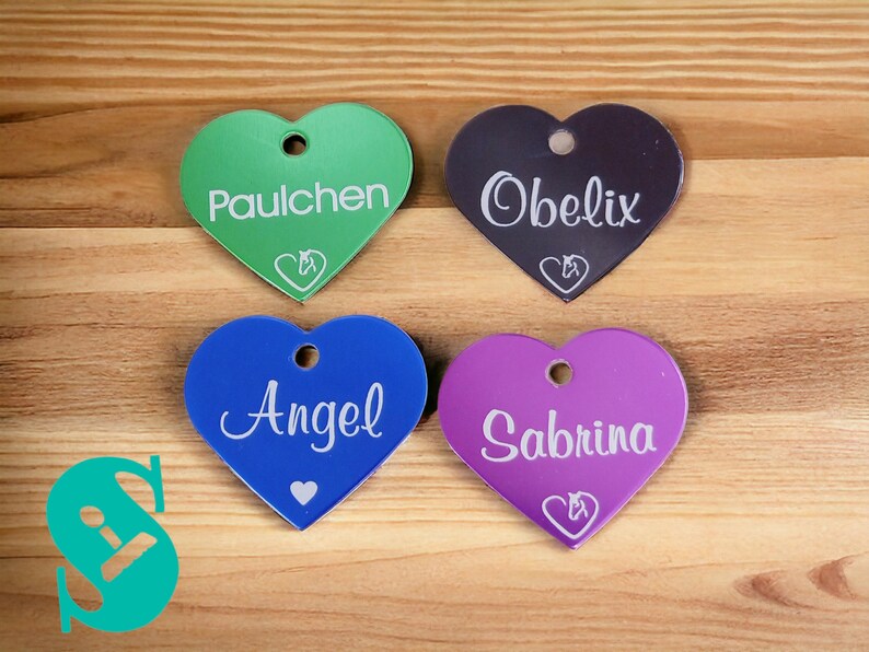 May include: Four heart-shaped acrylic tags with white text and a small horse silhouette. The tags are green, purple, blue, and black. The names on the tags are Paulchen, Obelix, Angel, and Sabrina.