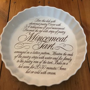 Puede incluir: Plato para tartas de cerámica blanca con texto marrón que dice "Line this dish with shortcrust pastry. Cover with 3-4 tablespoons of good mincemeat. Decorate the top with strips of pastry arranged in a lattice pattern. Moisten the ends of the pastry strips with water and fix firmly to the pastry rim of the tart. Bake in a hot oven for 20-30 minutes. Serve hot or cold with cream." El texto también incluye las palabras "Mincemeat Tart."