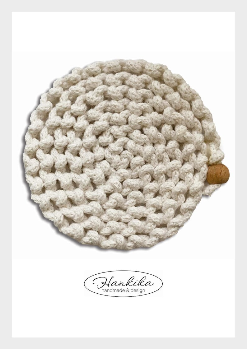 Puede incluir: Gorro de punto crema hecho a mano con un dise&ntilde;o anudado texturizado. El gorro presenta un peque&ntilde;o acento redondo de madera en el lateral. La imagen incluye el texto "Hankika handmade & design" en una fuente decorativa.