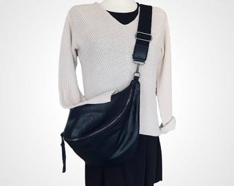 May include: A black leather crossbody bag with a long adjustable strap. The bag has a zipper closure and a small tassel.