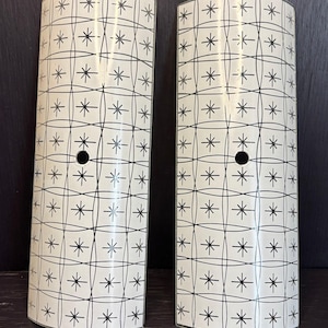May include: Two white glass lampshades with a black geometric pattern of stars and circles. The lampshades are curved and have a hole in the centre.