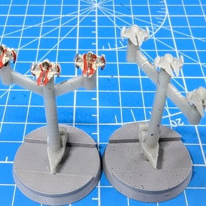 Puede incluir: Tres naves espaciales en miniatura pintadas de blanco y rojo en soportes. Las naves espaciales están sobre una base gris.