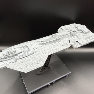 May include: A light grey model spaceship, the "Spirit of Fire", is displayed on a black stand. The model has intricate detailing and is set against a dark background. The text "SPIRIT OF FIRE" is visible on the side of the ship.