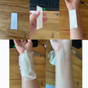 May include: A step-by-step guide on how to apply a temporary tattoo. The image shows a person applying a temporary tattoo to their arm. The tattoo is a simple design of a heart beat.