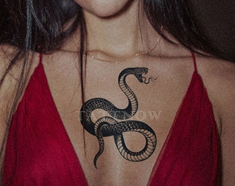 May include: A black snake tattoo design with a coiled body and a raised head. The tattoo is on a person's chest.