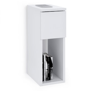 May include: A white ceramic mug with a black handle and the text "But First, Coffee" in a bold, black font. The mug is set against a blurred background, suggesting a cosy setting.