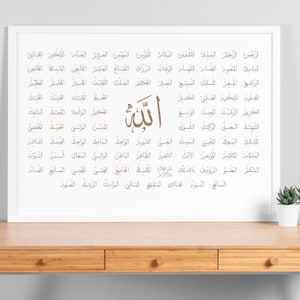 May include: A white framed print with a brown calligraphy design of the word "Allah" in Arabic script. The print features 99 names of Allah in Arabic script, arranged in a grid pattern.