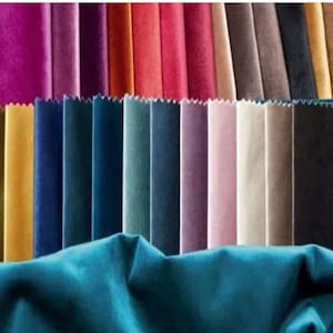 May include: A collection of colorful velvet fabric swatches in various shades, including teal, gold, blue, and pink. The swatches are arranged in a fan shape, showcasing the different colors and textures of the material. The image highlights the range of colors available.