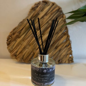 Könnte beinhalten: Eine klare Glasdiffuserflasche mit schwarzen Schilfrohren und einem silbernen Deckel. Die Flasche trägt ein Etikett mit der Aufschrift "New Beginnings Aromatherapy Diffuser Lavender Rose Bergamot & Rosemary".