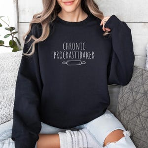 May include: A black sweatshirt with the text "Chronic Procrastbaker" and a white outline of a rolling pin.