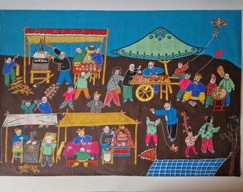 May include: A colorful folk art painting depicting a bustling outdoor market scene. Figures in various outfits are shown at food stalls, with a kite flying in the sky. The artwork features a brown background with blue and green accents.