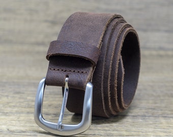 May include: A brown leather belt with a silver buckle. The belt is rolled up and the buckle is facing the camera.