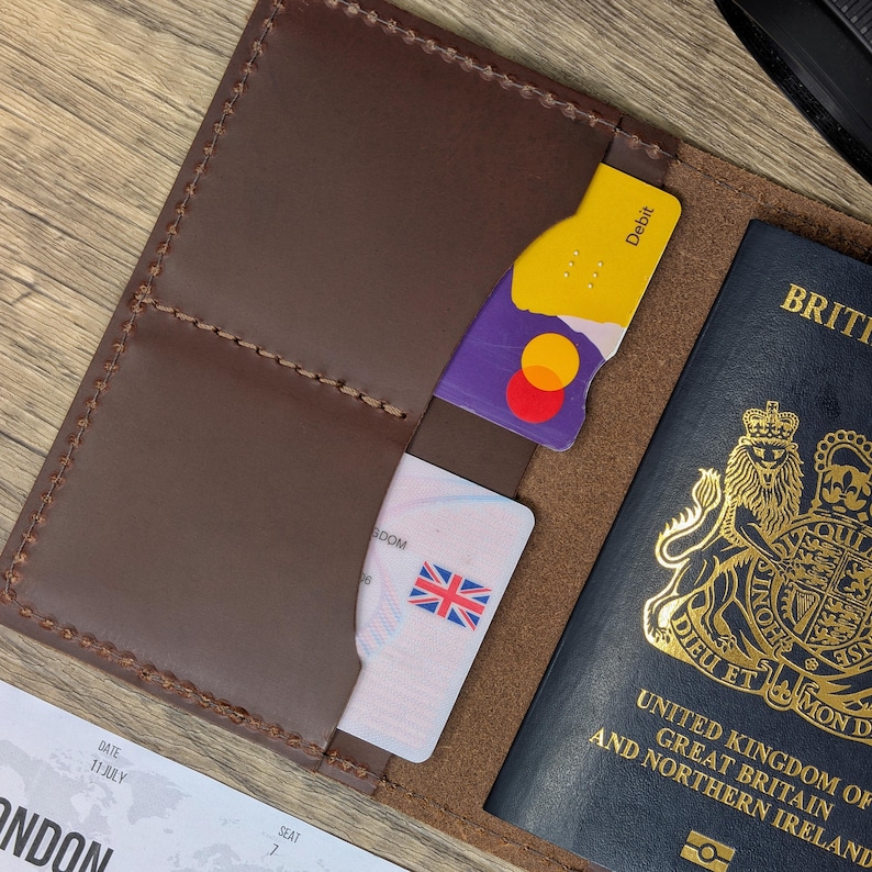 May include: A brown leather passport holder with a passport, credit card, and a boarding pass inside. The passport is a British passport with the text "United Kingdom of Great Britain and Northern Ireland" on the cover.