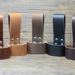 May include: Five leather belt loops in different colors: brown, tan, dark brown, black, and dark brown. Each loop has a silver metal rivet detail.