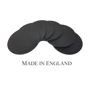 Könnte beinhalten: Satz mit sechs runden schwarzen Untersetzern, hergestellt in England.