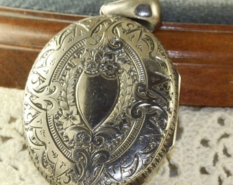 Puede incluir: Un medallón de plata con un diseño grabado ornamentado que presenta un centro en forma de corazón. El medallón tiene un bucle para una cadena y está en excelente estado.