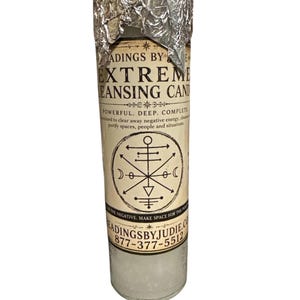 Puede incluir: Una vela blanca cilíndrica alta con una etiqueta que presenta el texto "EXTREME CLEANSING CANDLE". La etiqueta también incluye un símbolo y las palabras "POWERFUL. DEEP. COMPLETE". La parte superior de la vela está cubierta con papel de aluminio arrugado.