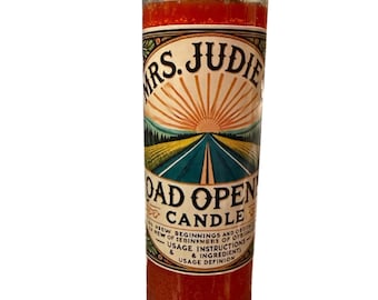 May include: A tall, cylindrical candle with a red wax interior. The candle's label features the text "MRS. JUDIE ROAD OPEN CANDLE" with a graphic of a road leading to a sunrise. Additional text includes "NEW BEGINNINGS" and "USAGE INSTRUCTIONS."