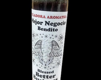 May include: Aromatic candle in a clear glass jar with a gold foil top. The label reads "Mejor Negocio Bendito" and "Blessed Better Business Aromatic Candle" with angel wings and star graphics.