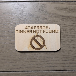 May include: A rectangular wooden sign with rounded corners. The sign features the text "404 ERROR: DINNER NOT FOUND!" above a graphic of a plate with a cake and a line through it. The sign is made of light-colored wood.