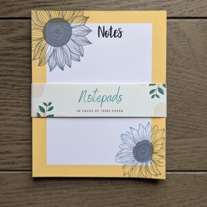 Könnte beinhalten: Gelber Notizblock mit Sonnenblumenmuster und dem Text "Notes" und "Notepads 30 pages of 70lbs paper".
