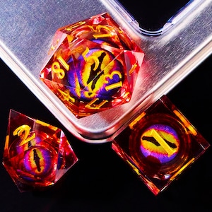 Könnte beinhalten: Drei rote und klare Würfel mit einem lila und gelben Augen-Design. Die Würfel sind mit 1, 2 und 13 nummeriert.