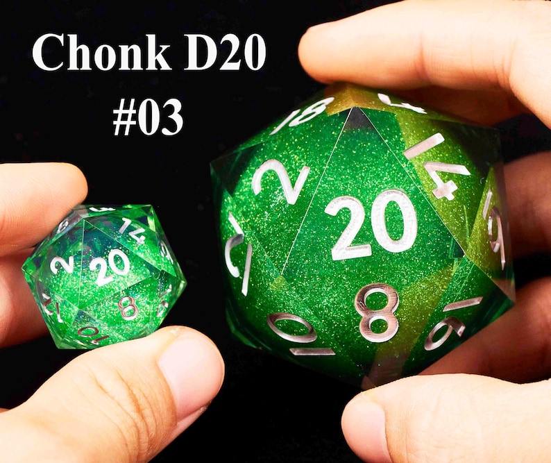 May include: Two green D20 dice with silver numbers. The larger die has a glittery finish and the smaller die has a smooth finish. The larger die has the number 20 on one side and the smaller die has the number 20 on one side. The text "Chonk D20 #03" is visible in the image.