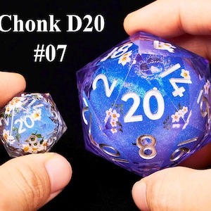 May include: Two purple and blue D20 dice with white numbers and floral designs. The larger die has the number 20 on the face and the smaller die has the number 20 on the face. The text "Chonk D20 #07" is in the top left corner of the image.