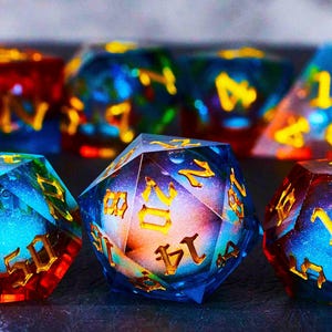 以下が含まれることがあります： 金色の数字が書かれた虹色のサイコロのセット。サイコロは、銀河のような模様の入った青、緑、赤です。