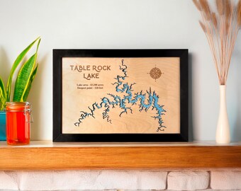 May include: A wooden map of Table Rock Lake with a compass rose in the top right corner. The lake is outlined in blue and the text "Table Rock Lake" is in brown. The text "Lake area - 43,100 acres" and "Deepest point - 220 feet" is also in brown.