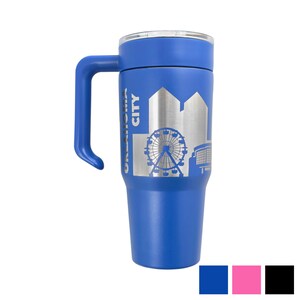 May include: A blue travel mug with a handle and a silver skyline design. The mug features the text "OKLAHOMA CITY" vertically along the side. The design includes a Ferris wheel and other city buildings. The mug has a black, pink, and blue color palette.