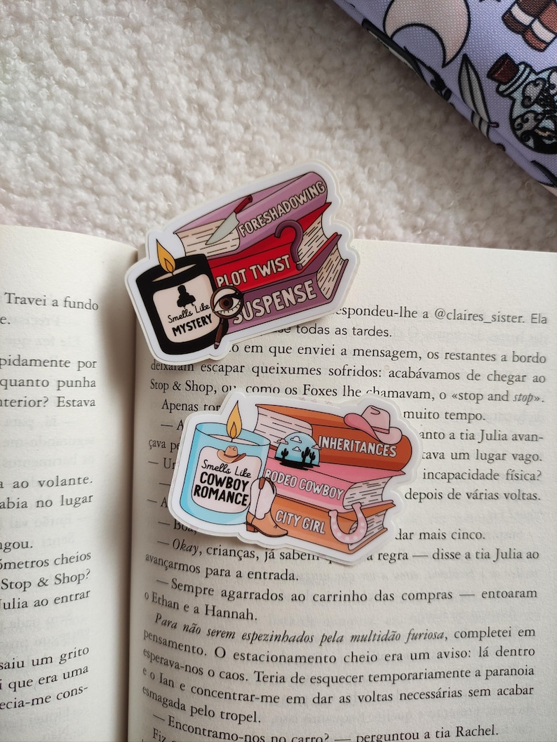 May include: Three colorful book stack stickers with a candle on top. The candle is labeled "Smells Like Cowboy Romance". The book stacks are labeled "Fore shadowing", "Plot Twist", "Suspense", "Inheritances", "Rodeo Cowboy", and "City Girl".