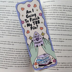 Op de afbeelding: Een grillige boekenlegger met een lichtpaarse rand, met de tekst "Am I Going To Finish My TBR Pile?" en een waarzeggerijontwerp. Inclusief harten, sterren, bloemen en een stapel boeken.
