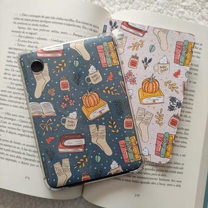 Op de afbeelding: Een blauwe en witte telefoonhoes met een herfstthema. De hoes heeft illustraties van boeken, pompoenen, koffiebekers en sokken. De tekst "Hello Fall" staat op de hoes.