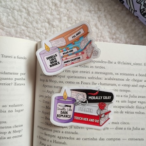 May include: Three colorful book-themed stickers with text that reads "Smells Like New Books", "Read One More Chapter", and "I'll Just". The stickers are layered on top of each other and feature a candle, a book, and a book with a bookmark. The stickers are on a white background.