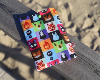May include: A colorful fabric pouch with a repeating pattern of characters from the animated film Studio Ghibli's Spirited Away. The pouch is made of a soft, durable fabric and features a zipper closure.