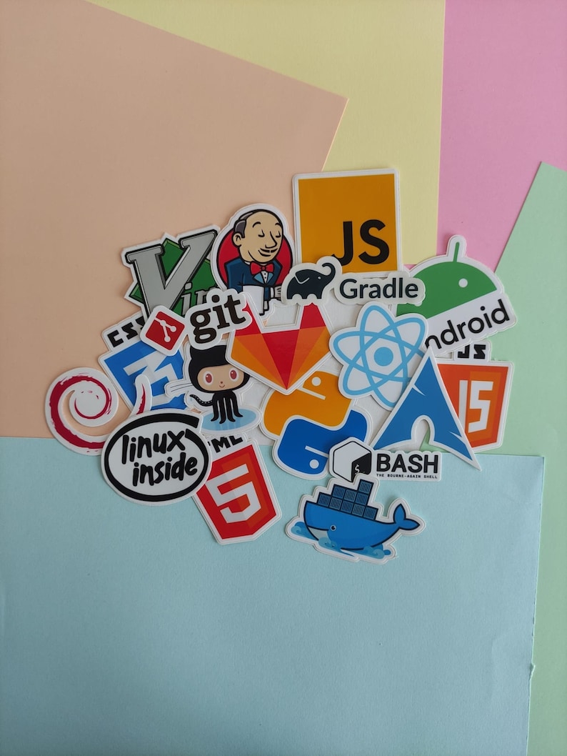 Peut inclure: Une collection d'autocollants color&eacute;s repr&eacute;sentant divers langages de programmation et technologies, notamment JavaScript, Git, Linux, Android et Bash. Les autocollants sont dispos&eacute;s sur un fond pastel.