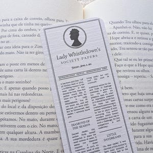 Pode incluir: Um marcador de livros com o título "Lady Whistledown's Society Papers" e a silhueta de uma mulher. O design assemelha-se a um jornal, com colunas de texto. Está sobre um livro aberto, sugerindo leitura.