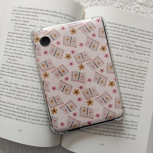 Può includere: Una custodia per telefono rosa e marrone con un motivo ripetitivo di libri aperti e fiori.