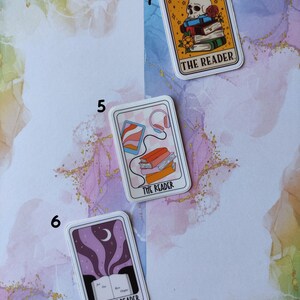 K&ouml;nnte beinhalten: Drei illustrierte Tarotkarten-Aufkleber mit rosa, lila und gelbem Hintergrund. Die Aufkleber zeigen den Text "The Reader" und "The Night Reader".